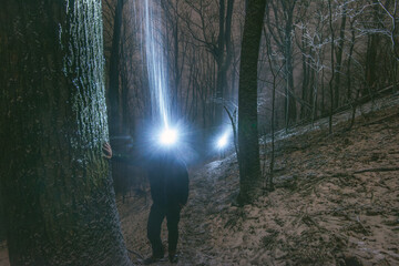 Two men with headlamps walk along a trail in an old growth forest at night during a snowstorm, Blowing Rock, North Carolina