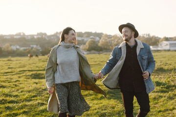 Stylish romantic couple walking in a field and posing for a photo