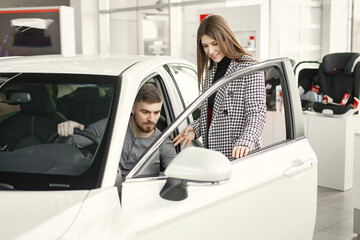 Caucasian young couple examining car at showroom