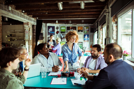 Team meeting with diverse group of professionals discussing project in a modern office
