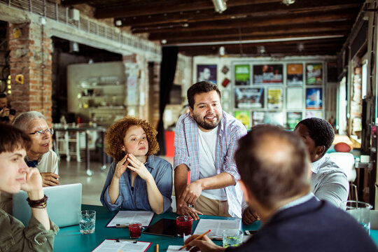 Team meeting with diverse group of professionals discussing project in a modern office