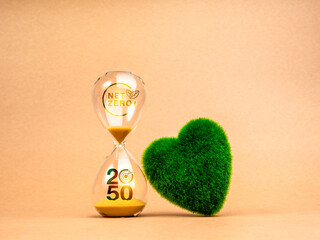Countdown to NET ZERO emissions reduction, environment sustainability concept. NET ZERO icon and 2050 year number with target symbol on hourglass and green grass heart shape ball on brown background.