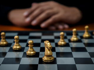 Gold horse, knight chess piece and gold pawn chess pieces on chessboard with businessman on dark background. Leadership, follower, team, commander, competition, and business strategy concept.