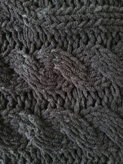 Detailed close-up view of a cozy knitted plaid with an intricate pattern in different colors. The fabric is soft and textured, allowing you to see the pattern up close.