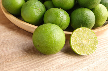 Natural fresh lime and lime cut in half on wooden table. Fresh ripe green limes on wooden table