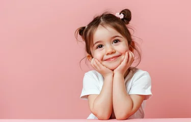 Rolgordijnen Cute little girl smiling and looking up, holding her chin with both hands on pink background © Kien