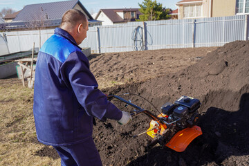 A man works in a vegetable garden in early spring.