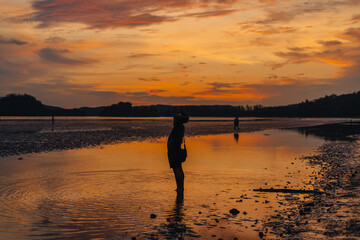 Silhouette of woman on calm beach and sky Evening at Ao Nang, Krabi