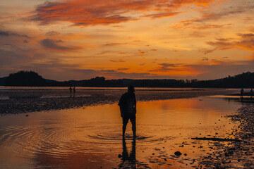 Silhouette of woman on calm beach and sky Evening at Ao Nang, Krabi