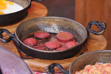 Cooking a dish of breakfast sausage in a pan on a wooden table