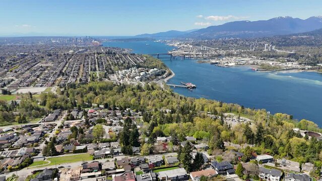 Panoramic aerial drone view (tilt up) of the skyline of Vancouver and Burnaby next to the Burrard Inlet during a spring season in British Columbia, Canada