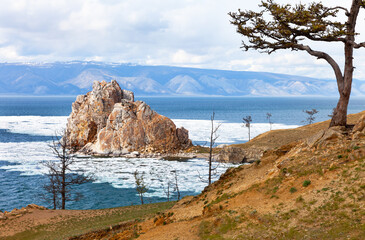 Spring Baikal Lake. Famous Shamanka Rock is natural landmark and place of attraction for tourists on Olkhon Island. Spring seascape with ice floes melting near Burkhan Cape. Natural background