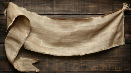 A large piece of cloth with a frayed edge is hanging on a wooden surface. The cloth is brown and has a rustic feel to it. The frayed edge gives the cloth a vintage and worn appearance - obrazy, fototapety, plakaty