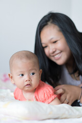 Infant Girl lifting her head with Asian Mother smiling