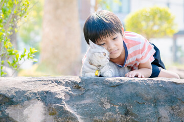 A boy and a cat sitting together in the park