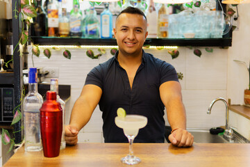 A man is sitting at a bar with a glass of margarita in front of him