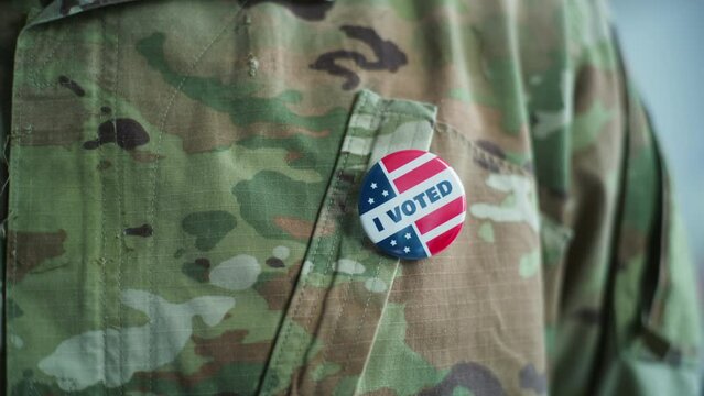 Close up of anonymous military man putting on badge with American flag logo and inscription I Voted. US Army representative at polling station after voting. National Election Day in the United States.