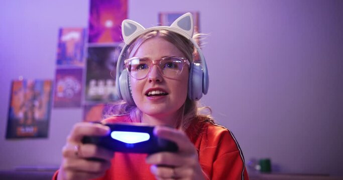 Headphones, woman and playing video game in home for competition, rpg and tournament online. Controller, girl and person on console technology for entertainment with neon light in apartment at night