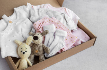 Baby and child clothes and knitted toys in carton box.