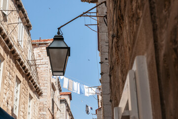 Laundry hanging high above the street between two old stone apartment buildings in European city