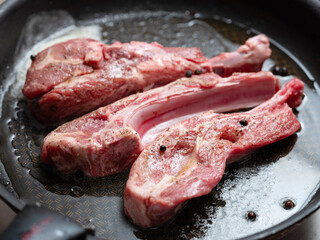 Raw lamb ribs in an iron pan
