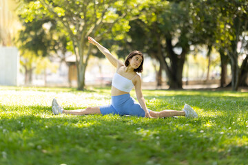 A woman is doing a yoga pose in a park