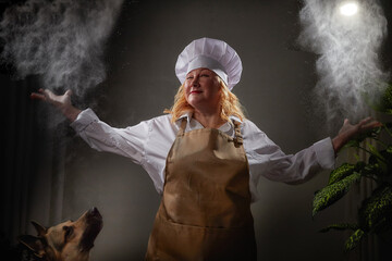 A fat funny female cook in a hat and apron in the kitchen with big shepherd dog. Good cooking, body positive, pet