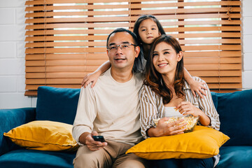In their comfortable living room family enjoys quality time watching TV with popcorn. father mother son daughter and schoolgirl are all smiles fostering togetherness and happiness.