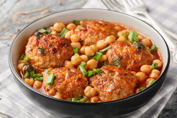 Homemade meatballs served with chickpeas, tomato and green onions close-up in a bowl on the table....