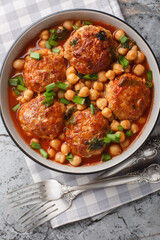 Lamb meatballs stewed with chickpeas in tomato-mint sauce close-up in a bowl on the table. Vertical top view from above