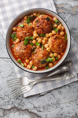Middle Eastern Lamb meatballs with chickpeas in tomato sauce close-up in a bowl on the table. Vertical top view from above