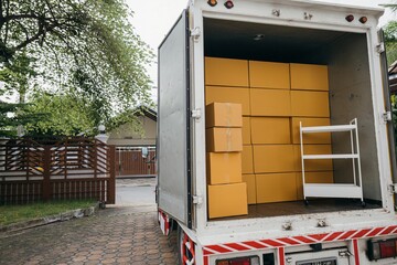 House relocation, Open car trunk with moving cardboard boxes outdoors. White delivery van for...