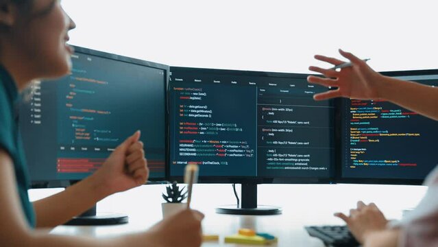 Slow motion back end software developer engineer for computer programming working together on debugging writing computing code, solving complex algorithms display on monitor in office. Burgeoning