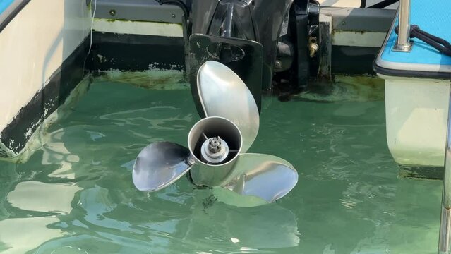 Close up stainless steel motor boat propeller on turquoise sea water background