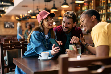 Group of happy friends using cell phone in  pub.