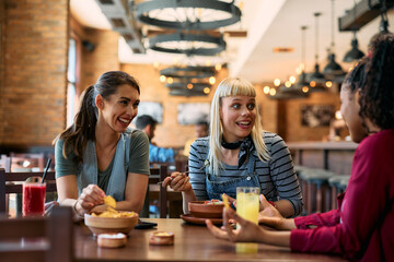 Young happy women having fun while gossiping and eating in  pub.