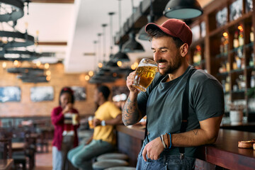 Young man enjoying in a glass of beer at bar counter.