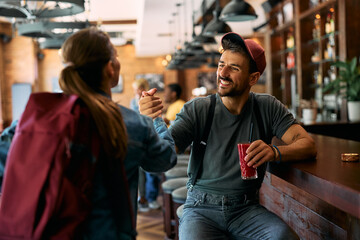 Young happy man greeting his female friend in cafe.