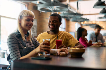 Happy black man having  drink with his girlfriend in bar.
