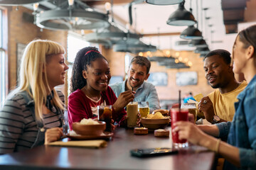Happy black woman enjoying in gathering with her friends in bar.