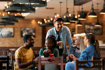 Group of happy friends talking while gathering in  pub.