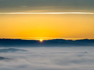 First rays of light appear of the sun new day dramatic sunrise mountains foggy morning