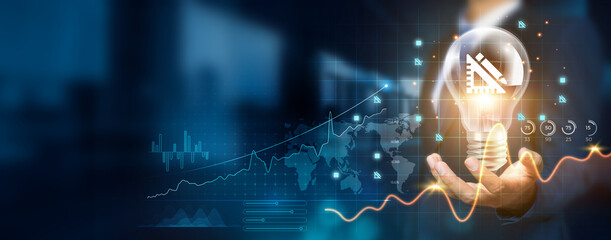 Businessman holding creative light bulb with growth graph and architectural icons. Utilizing innovative technology to design new structures and frameworks that optimize successful outcomes and profits