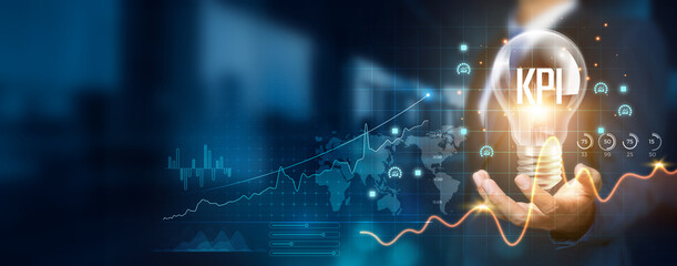 Businessman holding creative light bulb with growth graph and KPI icons. Leveraging innovative technology to develop new strategies and tactics that enhance successful and profitable operations.