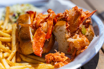 A lobster roll and French fries on a plate in a restaurant.