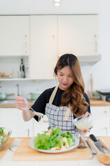 Young asian woman use spoon to adding mayonnaise into salad on plate while preparing fresh vegetables salad in bowl and cooking healthy breakfast food in modern kitchen with healthy lifestyle at home - 788991188