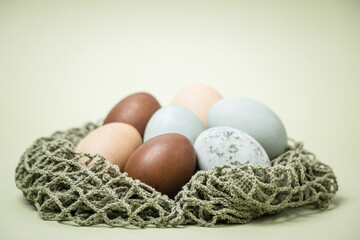 blue-gray and brown chicken eggs for Easter on a light green background.