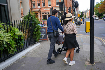 traditional couple walking the baby in the carriage on the streets of London.