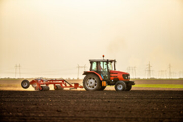 Sturdy tractor with plow attachment turns soil in a vast, open farmland