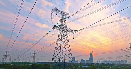 Aerial view of high voltage electricity towers and city skyline at sunset - Powered by Adobe